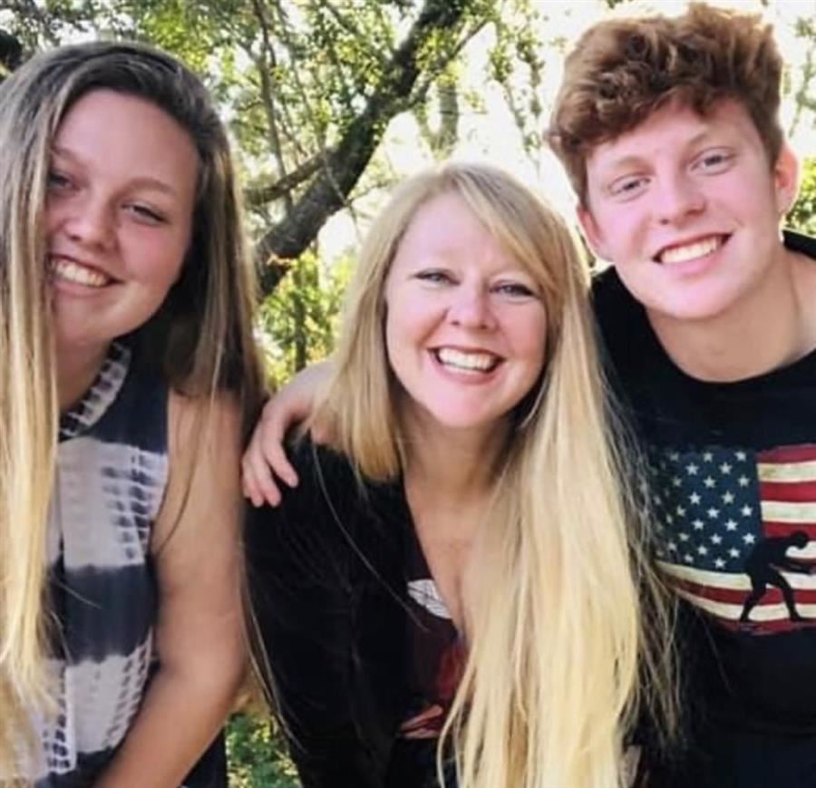 Alex smiles to camera with her son and daughter.